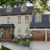 Exterior of a house painted in Benjamin Moore Rockport Gray, featuring a stylish front porch, large windows, and a modern garage design.