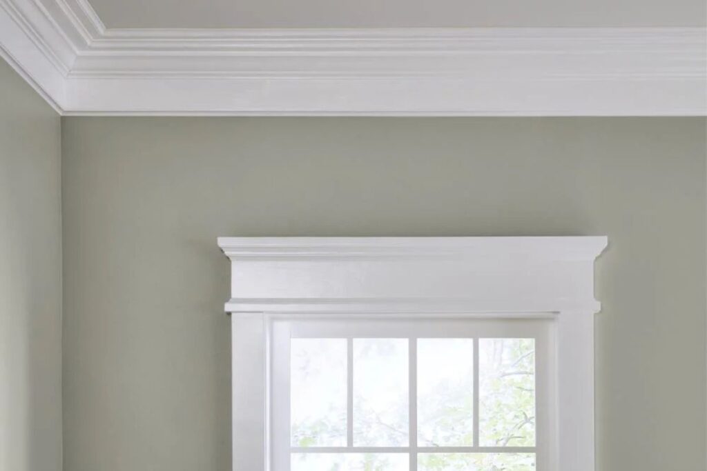 A window framed with white trim, showcasing soft green walls with white walls white trim at the top and bottom of the frame.