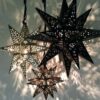 Moravian Star Lights with intricate cut-out designs, casting beautiful patterns on the wall, adding unique lighting to home decor.