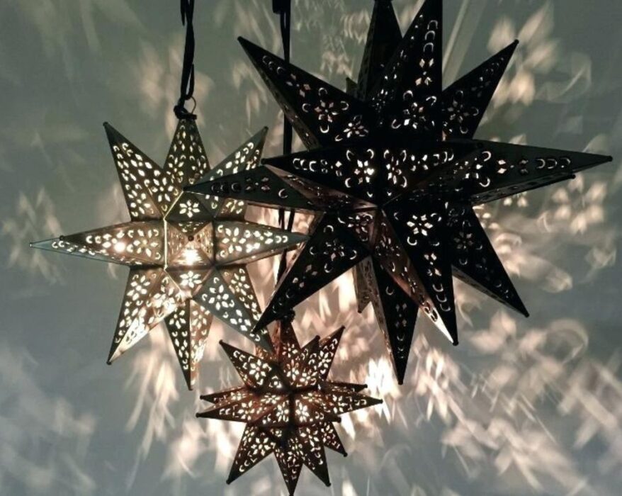 Moravian Star Lights with intricate cut-out designs, casting beautiful patterns on the wall, adding unique lighting to home decor.